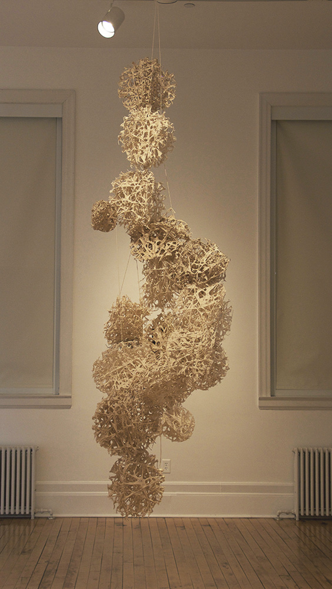 "Rhizome" hangs elegantly from the ceiling, displaying open airy spheres created from kozo covered threads. 