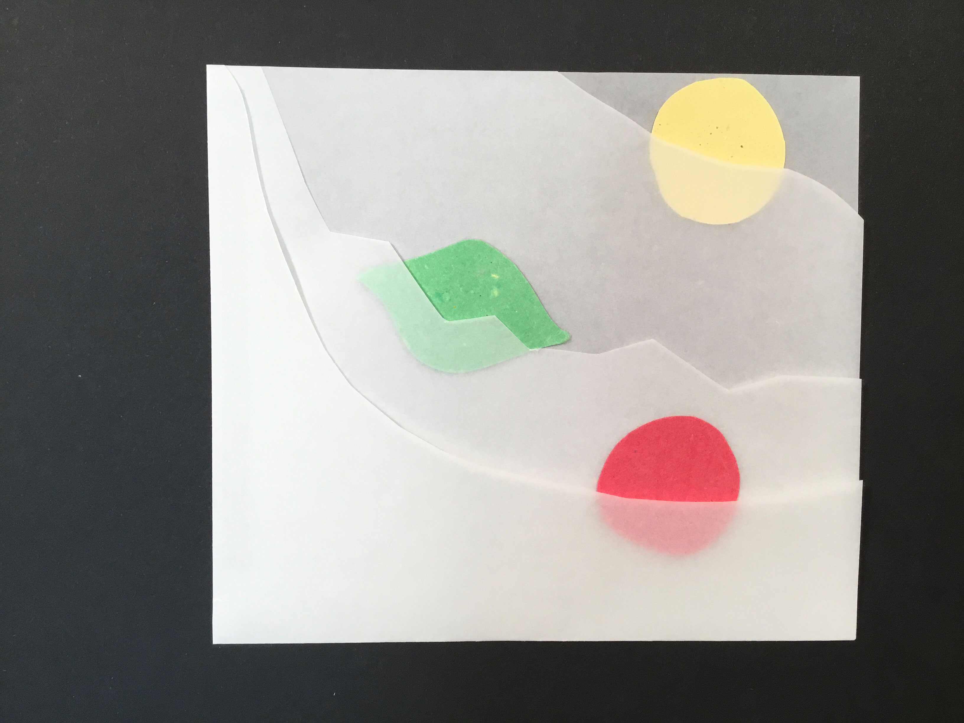 4 layers of translucent paper, each with the top right angle cut out in varying patterns. In the top right corner, between the base and second layer, is a yellow paper circle. In the center left, between the second and third layers, is a green paper lime. In the bottom right corner, between the third and fourth layers, is a red paper circle.