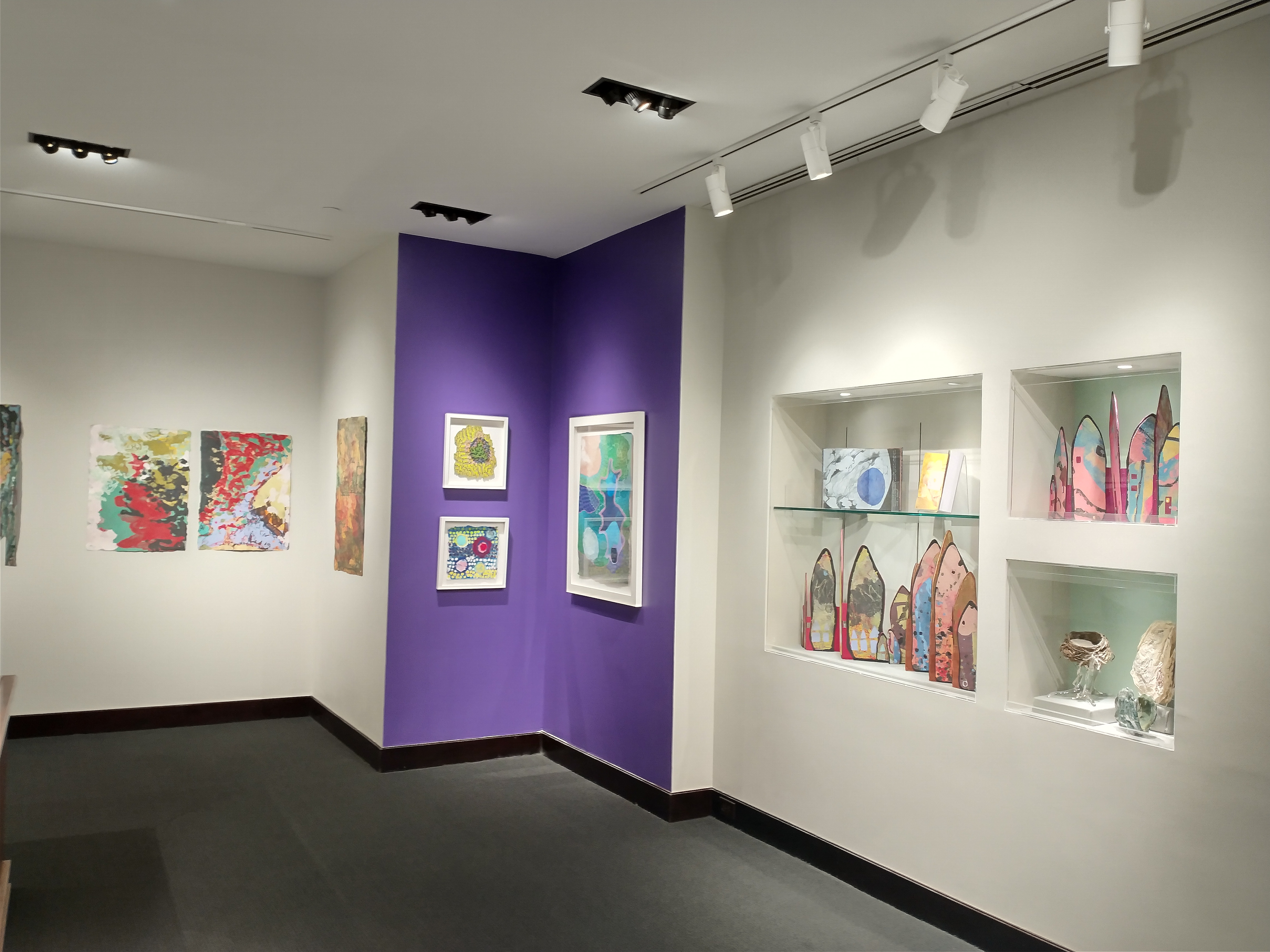 Photo looking across the large gallery to the purple accent corner and adjacent inset wall cases.