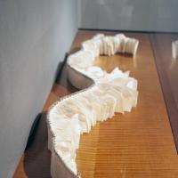 "La Cordillera is the Spine" is created from hand-torn folios of various sizes bound together by attaching Islamic-style handmade paper to a wire using a beautiful headband stitch across the full length of the book. Smaller bits of paper are clustered on either end of the book, gradually progressing to larger sheets as they come towards the middle. The wire within in the spine of the book is arranged to mimic the curvature of the human spine.
