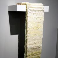 "Sprout" is a book that cascades over the edge of a shelf. The various lengths of bound abaca and kozo papers dyed in shades of green create an ombre that hangs in space out away from the wall. 