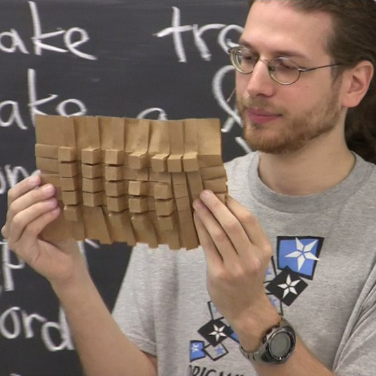 Computer Scientist, Mathmatician, and Artist Erik Demaine holding a single page fold during one of his lectures Erik Demaine 