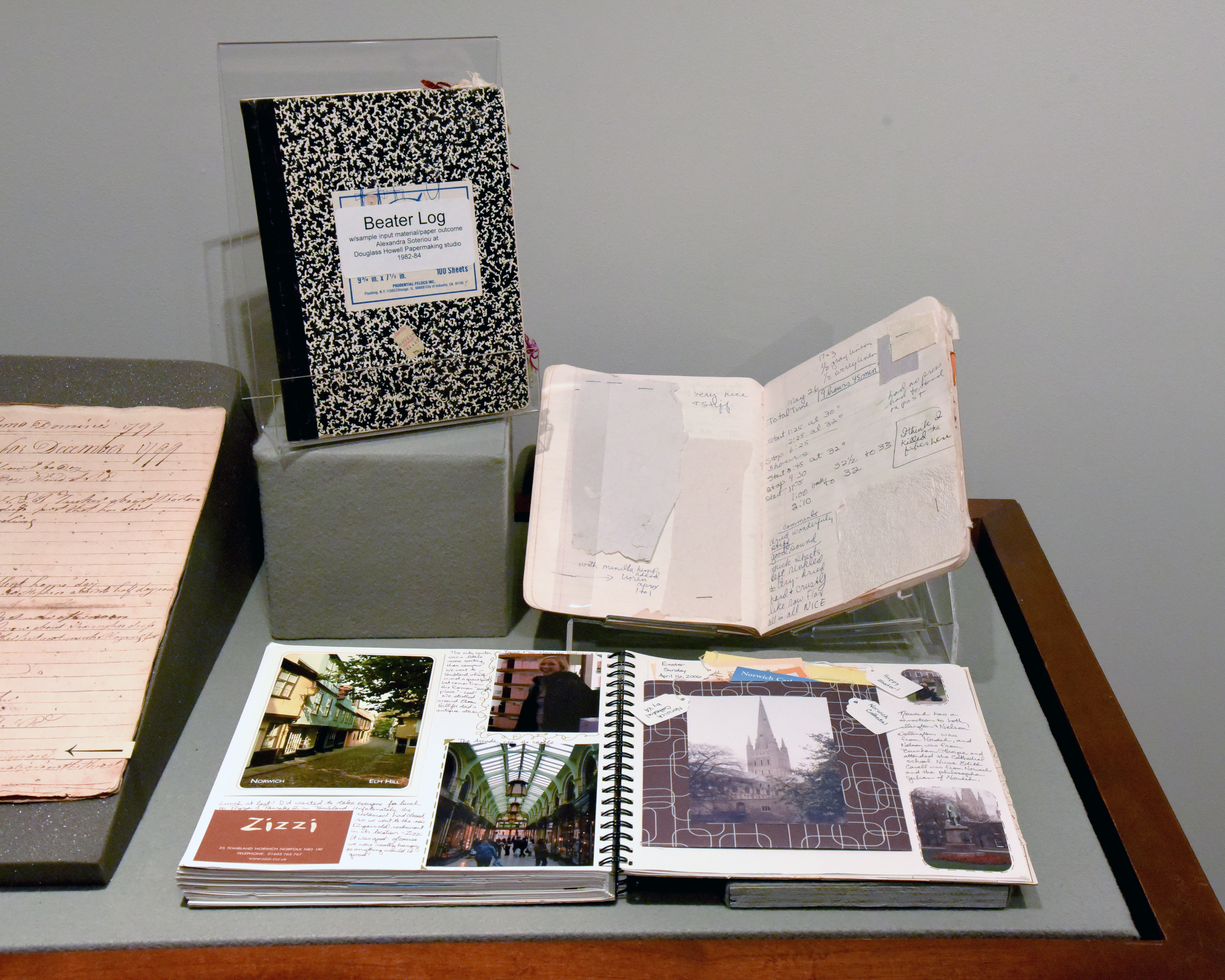 Black and white composition books turned into beater logs of recipes for handmade paper sit just behind a travel scrapbook