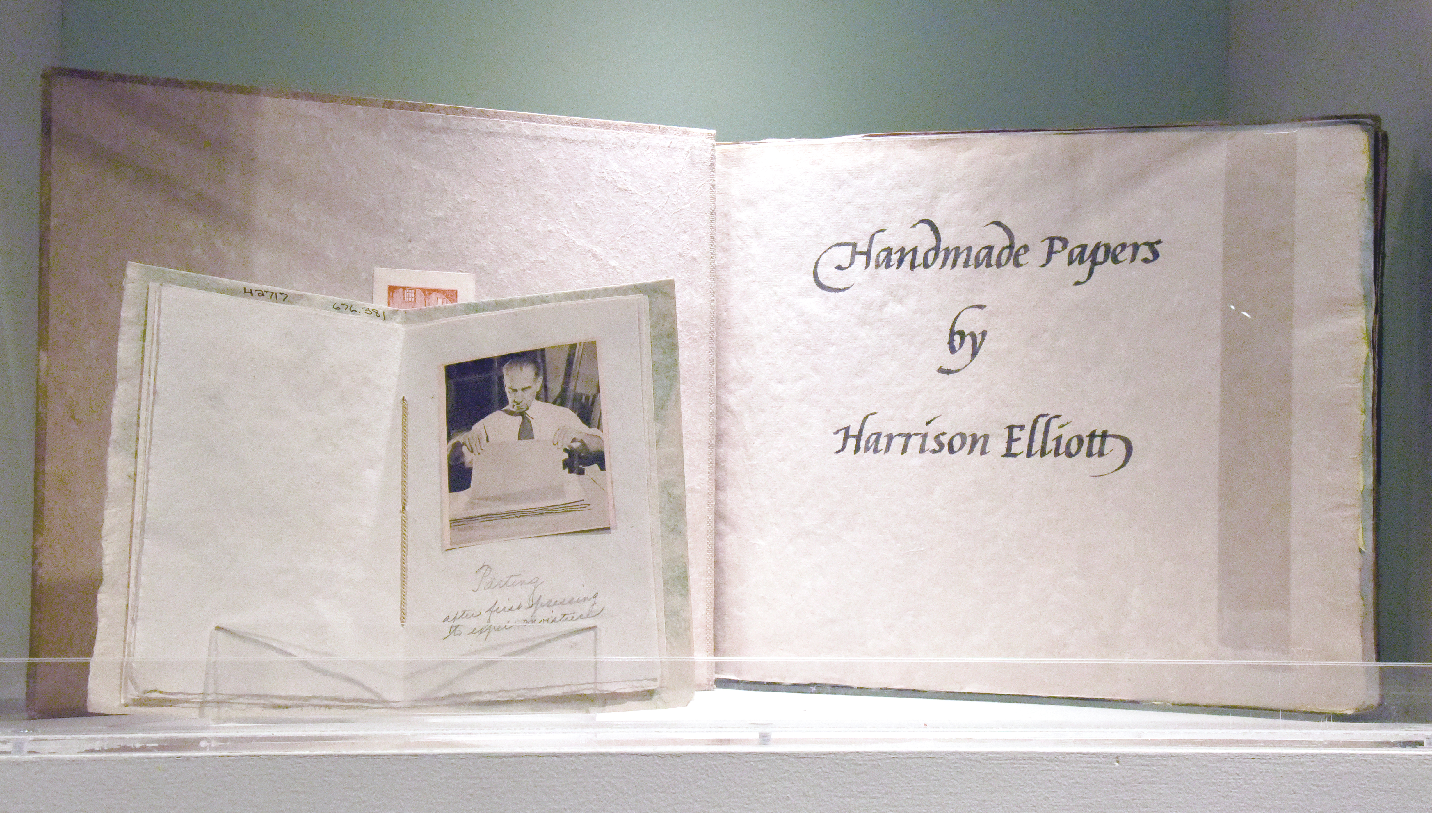 Small pamphlet featuring newspaper clippings featuring photos of Harrison Elliott making paper sitting in front of an album of handmade paper samples made by Elliott