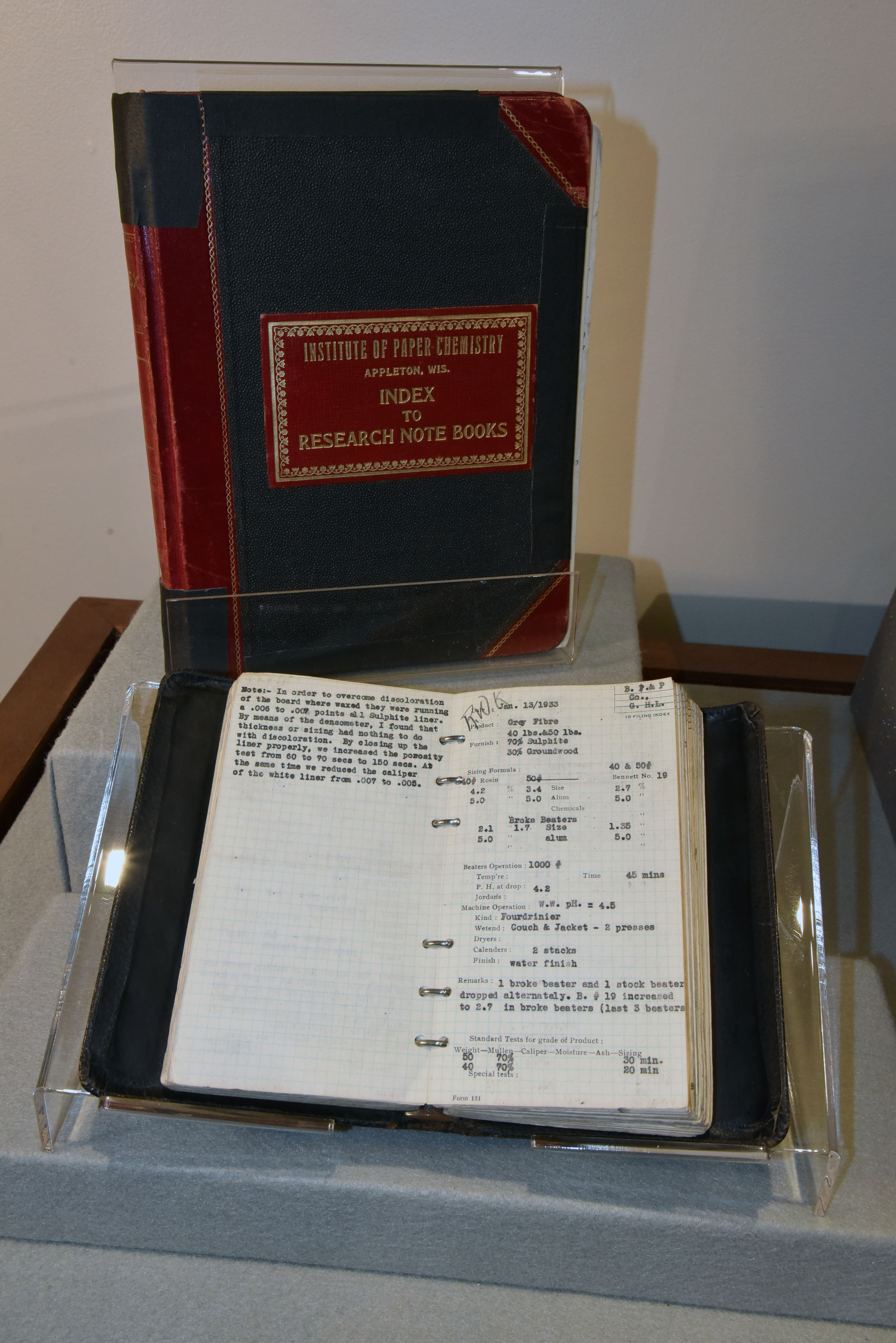 Two research notebooks of the Institute of Paper Chemistry. One is closed to show the cover and the other is opened to revealed typed notes of an experiement