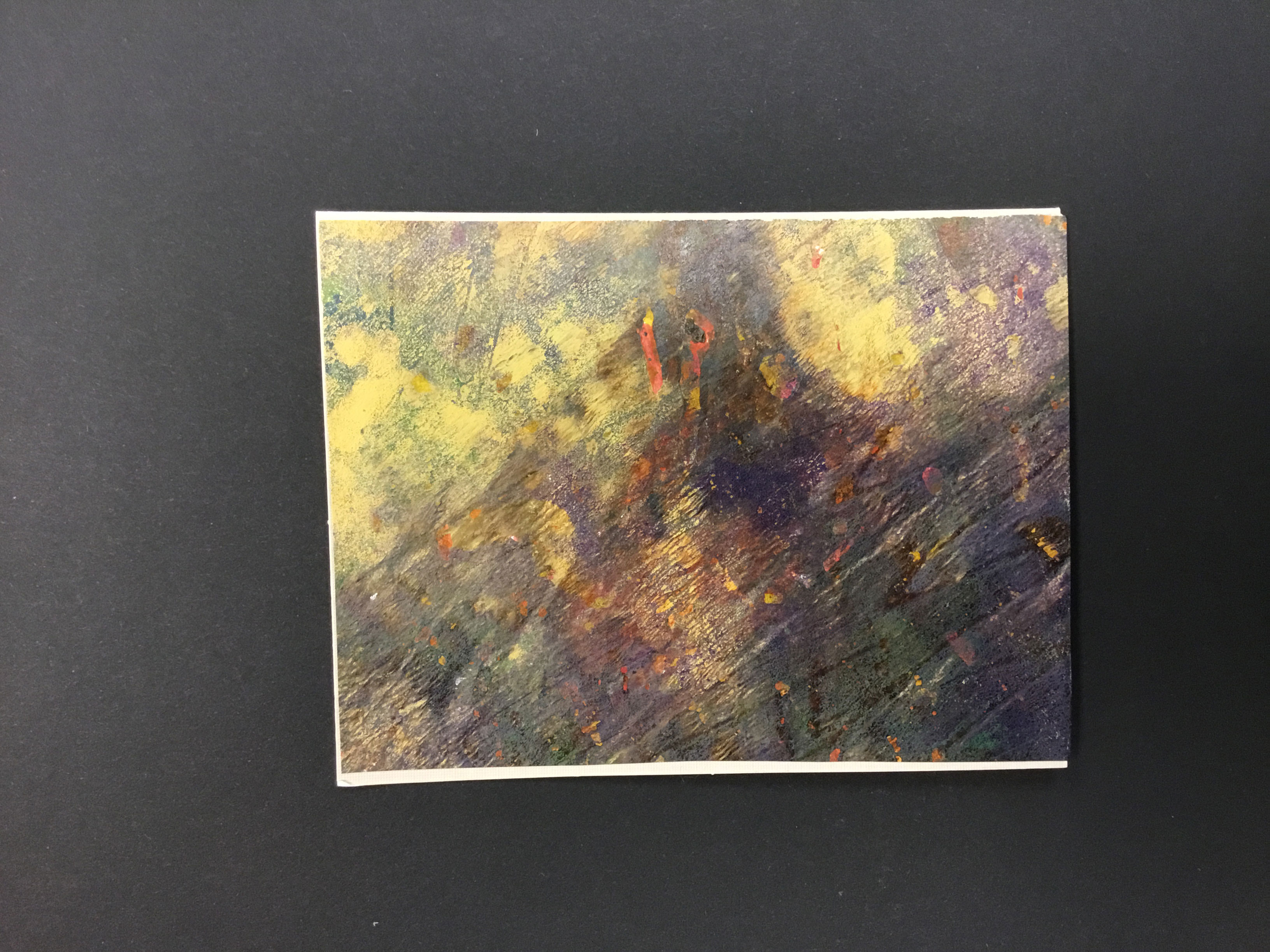 A piece of paper with an eco-print made from natural materials and acrylics. The print is comprised of abstract inkings of yellow, orange, navy, and forest green.