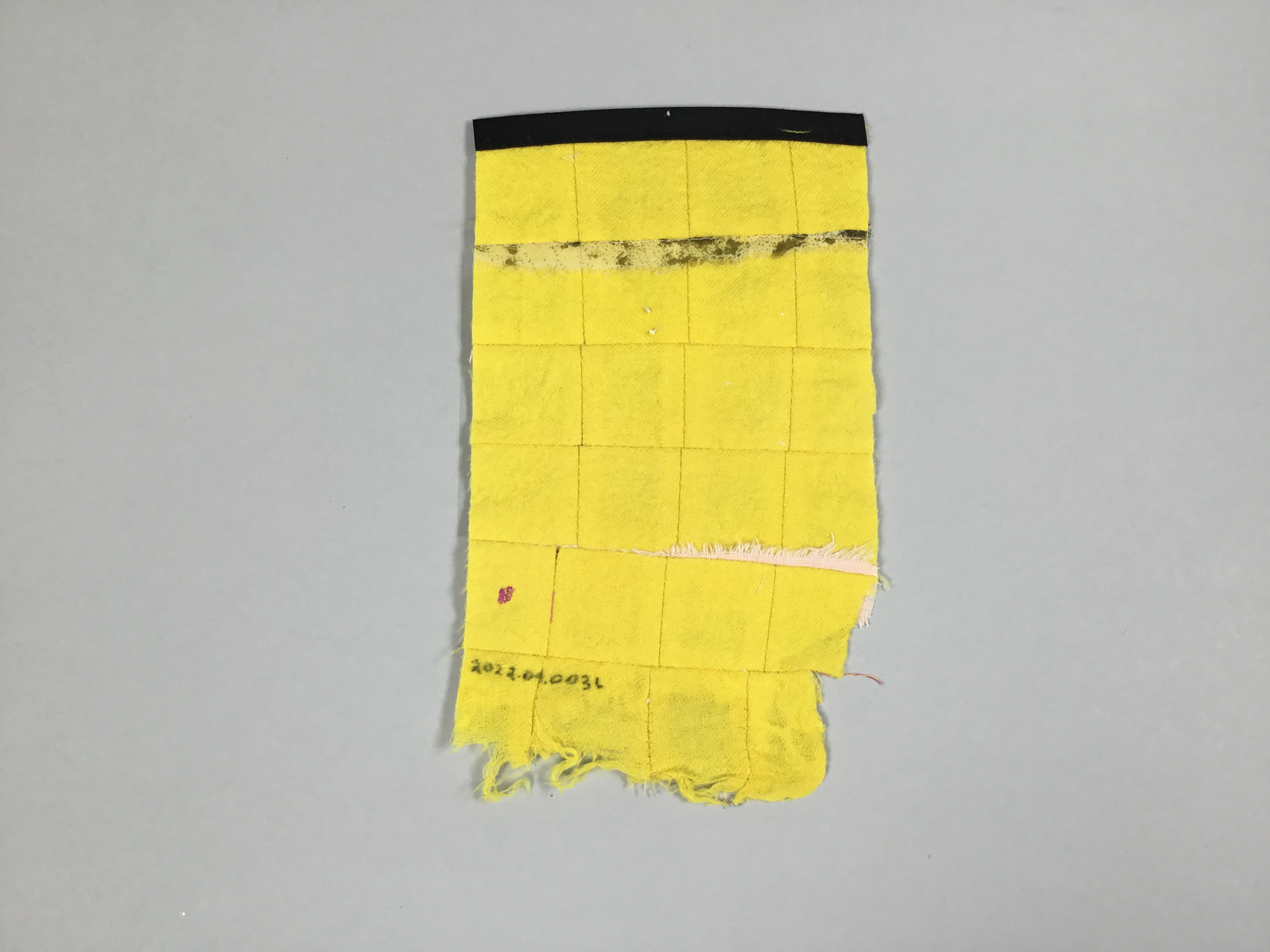 This piece, entitled “Don’t Be Afraid of Me”, is a yellow and beige quilted rectangle made of fabric scraps. The right side of the piece has a translucent sheet with a poem printed onto it.
