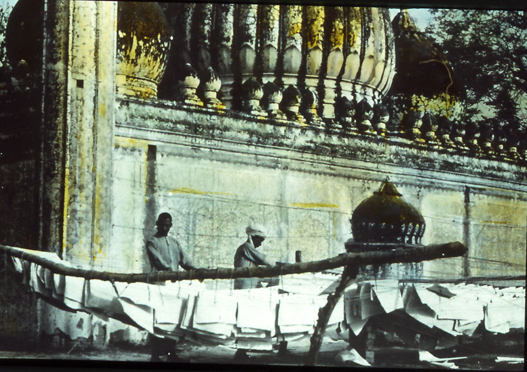 Hand tinted glass slide of handmade paper hung outside to dry in India. Original photo taken by Dard Hunter.