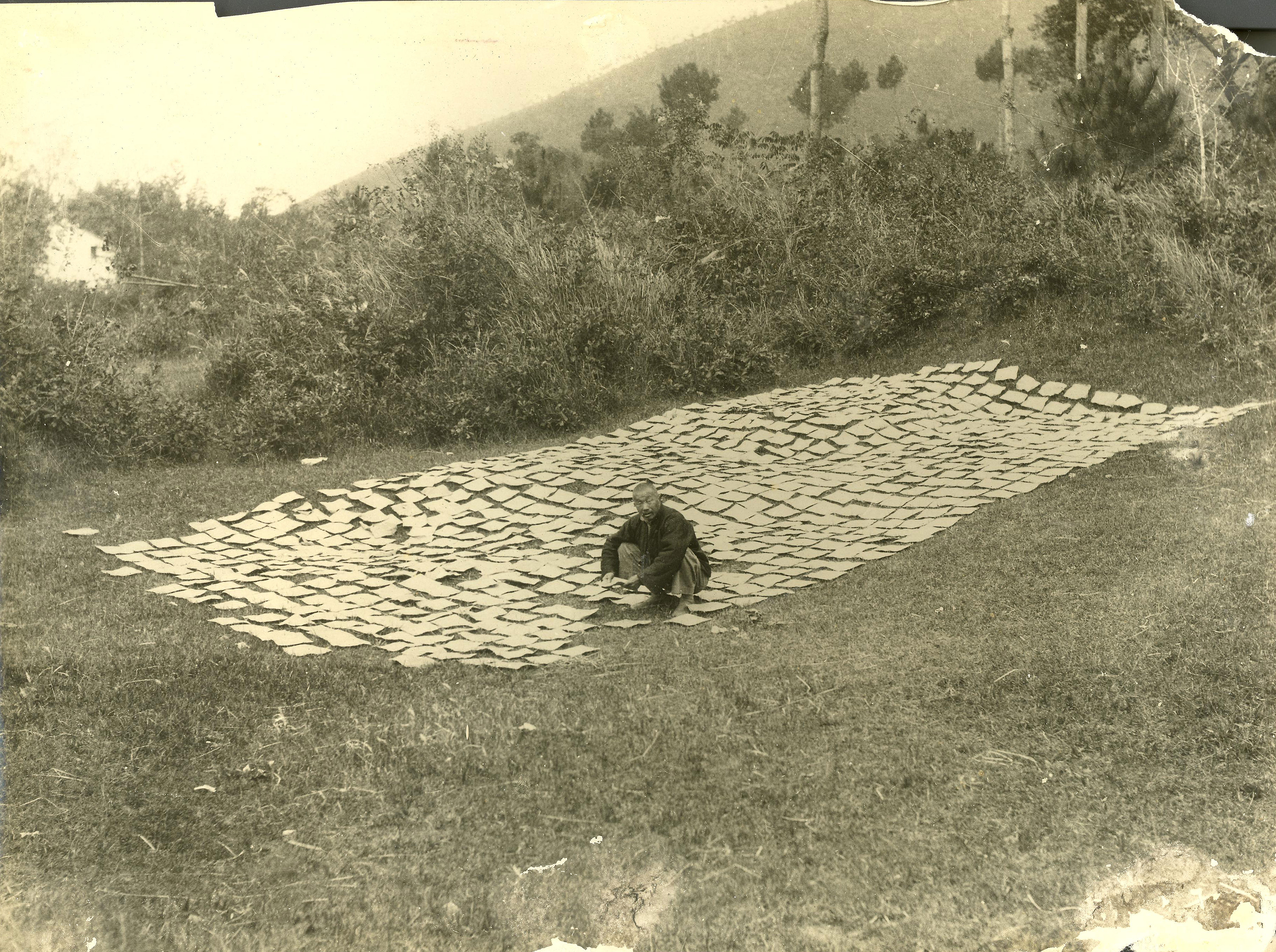Chinese man sitting in a field of drying handmade papers