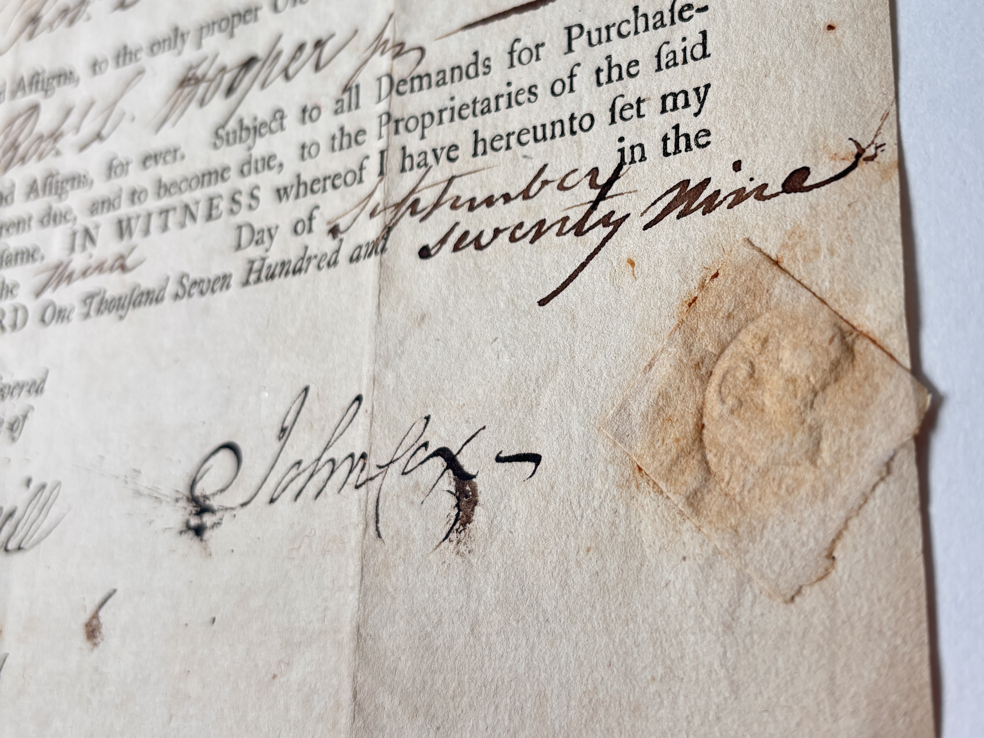 Side angle of the tan paper with an embossed seal on it.