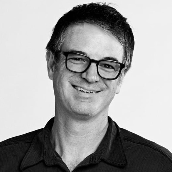 Bio headshot of Jon Dilling, Senior Video Editor for Warner Media. The photo is black and white. Jon is a Caucasian man with dark hair, wearing glasses and a dark shirt. He is smiling directly at the camera with is head slightly tilted.