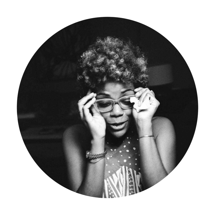 Black and White photo of Dr. Kimberly Diana Jacobs, an African American woman lifting her hands to adjust her glasses