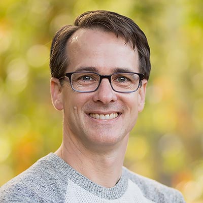 Chris Muhlstein- photograph of man facing the camera and smiling.