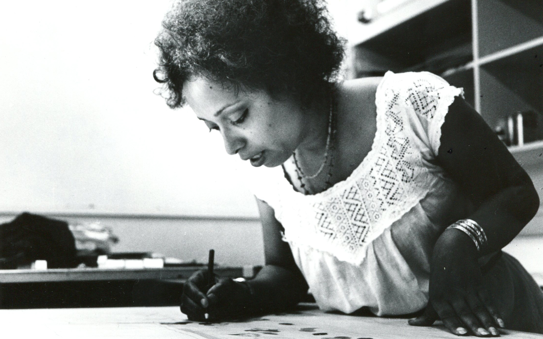 Black and white photo of Margo Humphrey, African American artist leaning over a table drawing