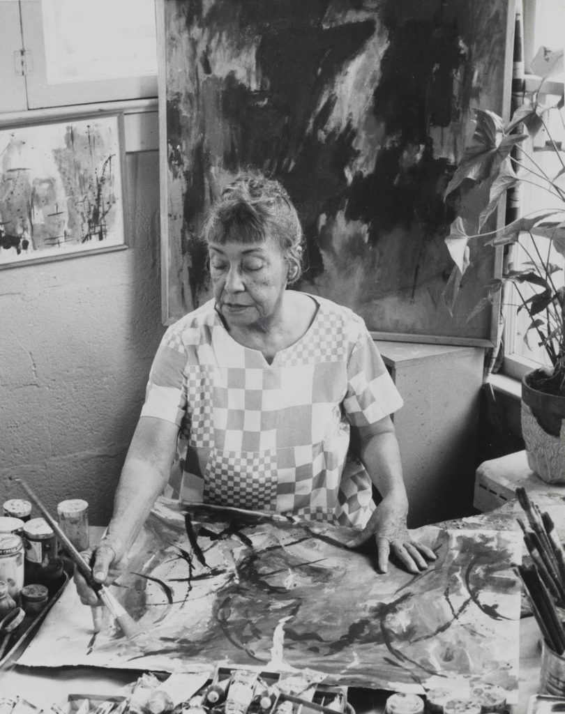 Black and white photo of Alma Thomas painting in her studio