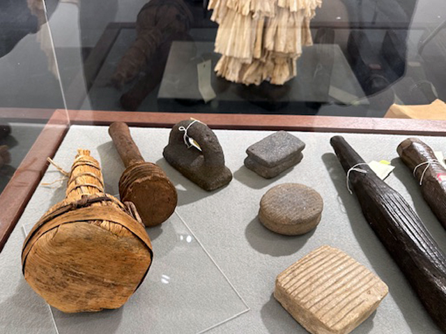 A closeup of a case with various bark beaters made of wood and stone.