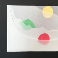 4 layers of translucent paper, each with the top right angle cut out in varying patterns. In the top right corner, between the base and second layer, is a yellow paper circle. In the center left, between the second and third layers, is a green paper lime. In the bottom right corner, between the third and fourth layers, is a red paper circle.