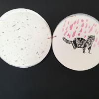 A circular sheet of paper with a painted image of a weasel or ferret on it with pink rain in the background. 