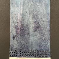 A rectangular piece of flax paper unevenly dyed with indigo and with four rows of small circular perforations above a thin band of beige at the bottom.
