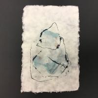 This piece is a rectangular piece of off-white handmade paper with raw edges. The center features a splash of light blue pigment, as well as black sketches of ink surrounding it.