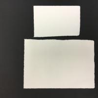 Two sheets of white handmade paper with raw edges and made entirely from cotton rag.