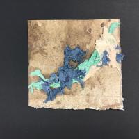 An almost-square piece of handmade paper with raw edges that has a variety of shades of brown across it. In the foreground of the piece are three diagonal layers of blue, teal, and white twisted paper.