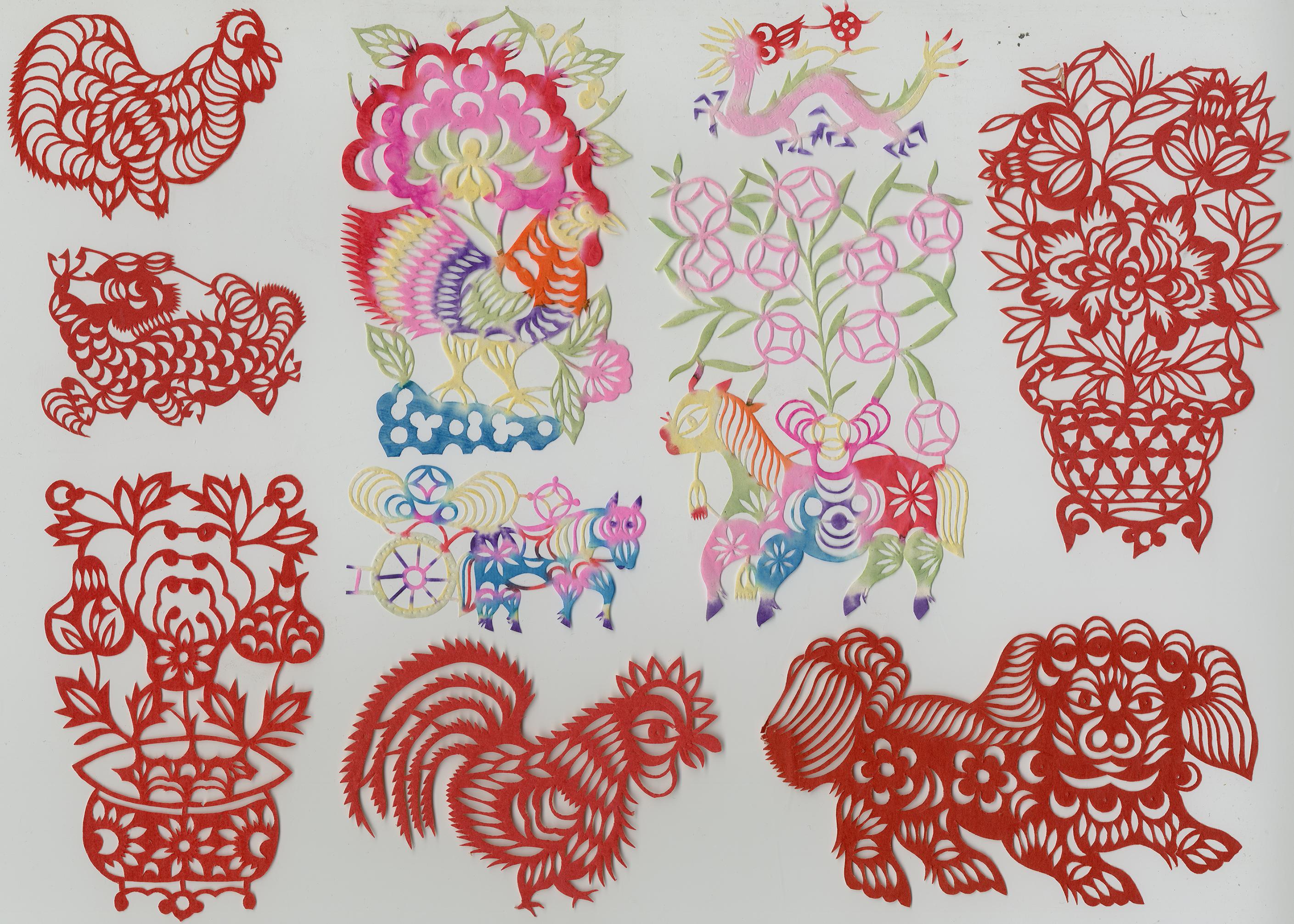 Assorted Chinese paper cuttings organized into a grid with the red cuttings along the border of the grid and the multicolored cuttings in the middle
