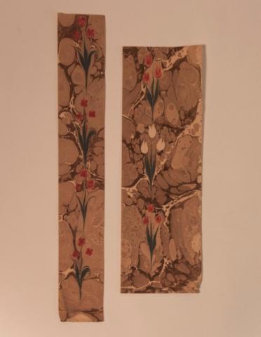 two rectangular sheets of marbled paper with red tulips overlaying a brown marbled pattern