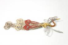 This image is of the whole ornament and the gold, silver, and red cords intricately woven into the shape of a crane with a long tale silver wings