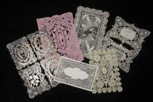 An image depicting an assortment of rectangular greeting cards with detailed lace designs, one of which is pink